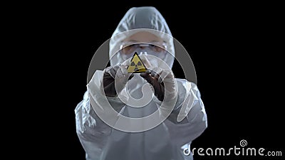 Scientist in protective suit showing ionizing radiation sign, black background Stock Photo