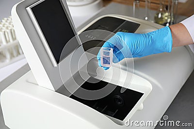 Scientist putting sample compartment with liquid in spectrophotometer. Laboratory analysis Stock Photo