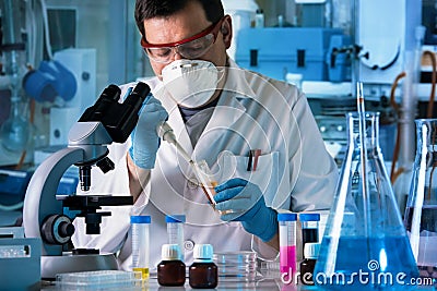 Scientist working in microscope with chemical material samples in biotechnology lab Stock Photo