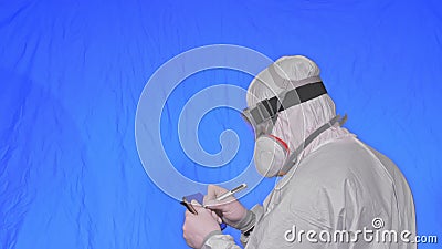 Scientist virologist in respirator makes write in an tablet computer with stylus. Man wearing protective medical mask Stock Photo