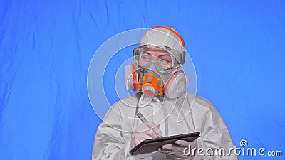 Scientist virologist in respirator makes write in an tablet computer with stylus. Woman wearing protective medical mask Stock Photo