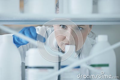 Scientist woman, shelf and bottle in lab with choice, thinking or idea for experiment, innovation or pharma career Stock Photo