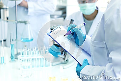 Scientists analyzing study data and evaluating microscope. Health care researchers doing some research with dropper chemical test Stock Photo