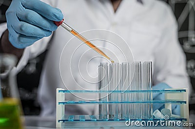 Scientists drop orange chemicals into the glass at the laboratory Stock Photo