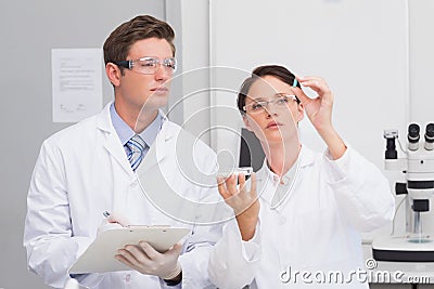 Scientists looking attentively at pill Stock Photo