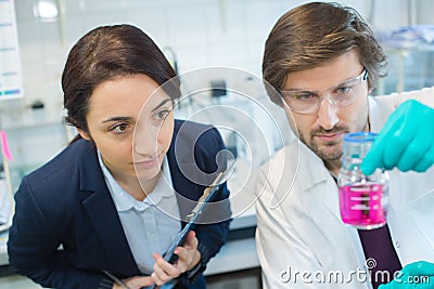 Scientists looking at pink liquid in glass flask Stock Photo