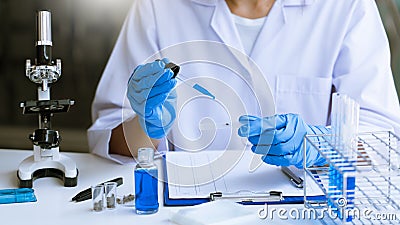 Scientists researching in laboratory in white lab coat, gloves analysing, looking at test tubes sample, biotechnology concept Stock Photo