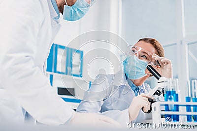 scientists in white coats, medical gloves and goggles making scientific research together Stock Photo