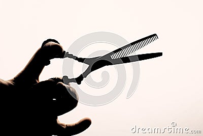 Scissors in the hand of the hairdresser silhouette on a light background Stock Photo