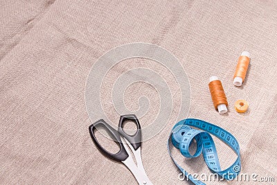 scissors, measuring tape and several spools of thread on linen fabric Stock Photo