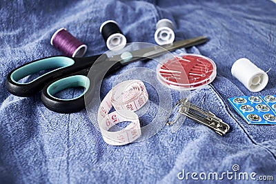 scissors needles measuring tape and thread on the background of torn jeans the concept of reasonable consumption of Stock Photo