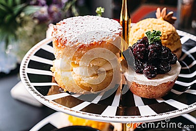 Scone Pie topping with icing and Blueberry Mini Tart on black and white plate. Dessert for afternoon tea Stock Photo