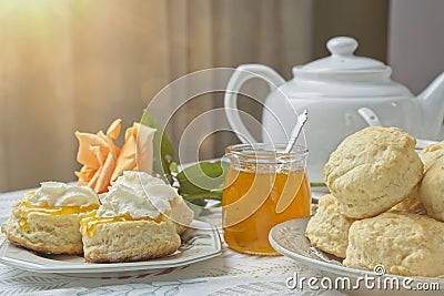 Scones with apricot jam and whipped cream on a table with jar of jam Stock Photo