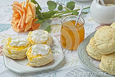 Scones with apricot jam and whipped cream on a table with jar of jam Stock Photo