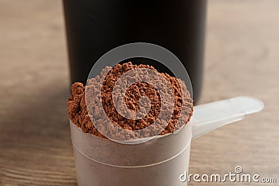 Scoop of chocolate protein powder on wooden table Stock Photo