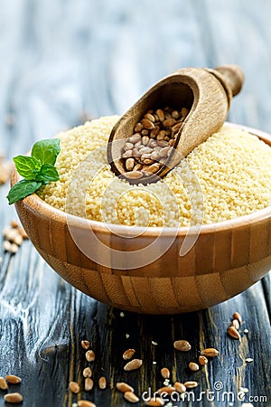 Scoop with wheat in a wooden bowl with couscous. Stock Photo