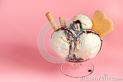 vanilla flavor ice cream in glass bowl with chocolate sauce, strewed sprinkles and waffle cookies on pink background Stock Photo