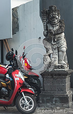 Scooter bikes parked next to a balinese statue Stock Photo