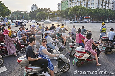 Scooters drivers wait for green light on an intersection in downtown Guilin at sunrise. Editorial Stock Photo