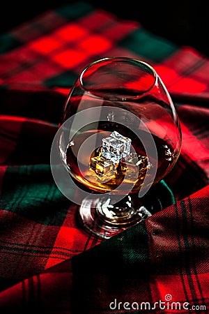 Scottish whiskey in a glass on tartan background Stock Photo