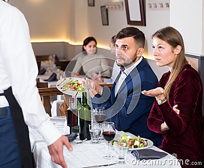 scowling guests conflicting with waiter in restaurant Stock Photo