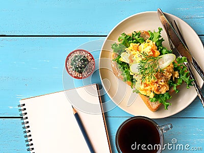 Scrambled eggs sandwich breakfast with empty notebook. Stock Photo