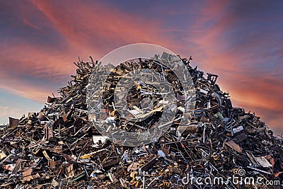 scrap metal heap at recycling junk yard against red sky Stock Photo