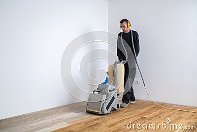 Carpenter doing parquet wood floor polishing maintenance work by machine Stock Photo