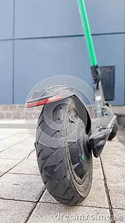 Scratched and damaged rear wheel of an electric scooter on a city street against the background of paving slabs. Old e-scooter Editorial Stock Photo