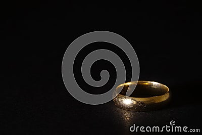 A scratched used old gold wedding ring on black background Stock Photo