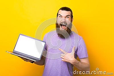 Screaming bearded man is pointing at the laptop. Stock Photo
