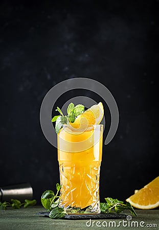 Screwdriver, classic alcoholic cocktail with vodka, orange juice and ice, garnished with fruit slice and mint. Dark background, Stock Photo