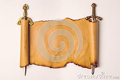 Scroll of old paper with burnt edges stretched on the blades of knightly swords, isolation on a white background. Stock Photo