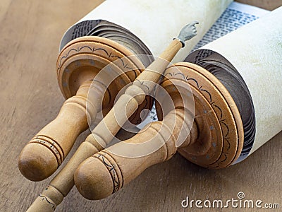 A scroll of Torah and a pointer on a wooden table, closeup. Stock Photo