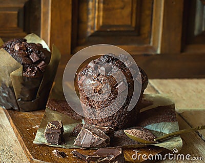 Scrumptious Home Baked Chocolate Chips Muffins in Brown Paper on Wooden Cutting Board. Cocoa in Spoon. Rustic Kitchen Stock Photo