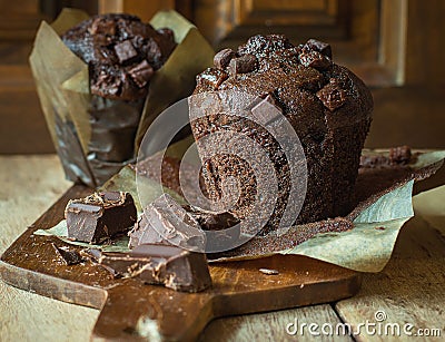 Scrumptious Home Baked Chocolate Chips Muffins in Brown Paper on Wooden Cutting Board. Rustic Kitchen Stock Photo
