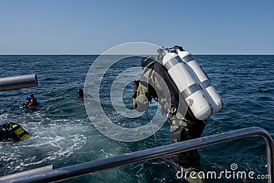 A scuba diver enters the water. Giant stride enter. Twin set tank. Ocean and blue sky in the background Editorial Stock Photo