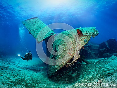 A scuba diver explores a sunken shipwreck in shallow waters Stock Photo
