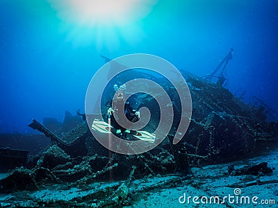 Scuba diver in front of a sunken shipwreck Stock Photo