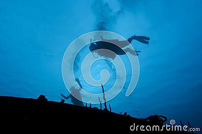Scuba diver hover over a shipwreck in silhouette Stock Photo
