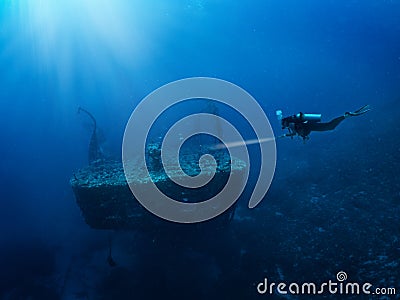 A scuba diver with a torch explores a sunken shipwreck Stock Photo