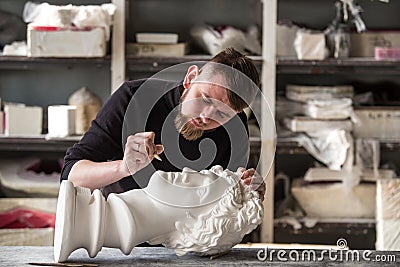 The sculptor conducts restoration work in a plaster workshop. Restoration of the gypsum head of Apollo Stock Photo
