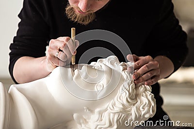 The sculptor conducts restoration work in a plaster workshop. Restoration of the gypsum head of Apollo Stock Photo