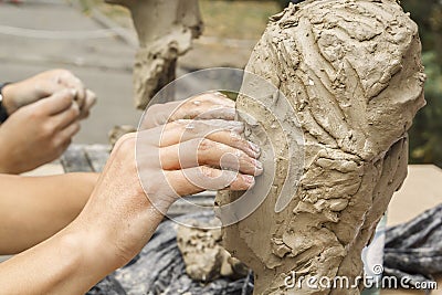 Sculptor creates a bust and puts his hands clay on the skeleton of the sculpture. Stock Photo