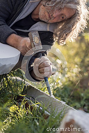 Sculptor sculpting with chisel and hammer in marble Stock Photo