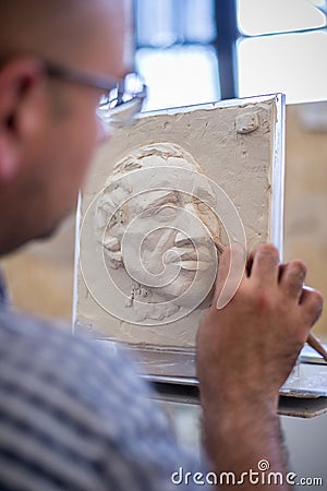 A sculptor sculpts a sculpture of a person`s face. Horizontal frame Editorial Stock Photo