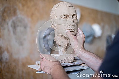 A sculptor sculpts a sculpture of a person`s face. Horizontal frame Stock Photo