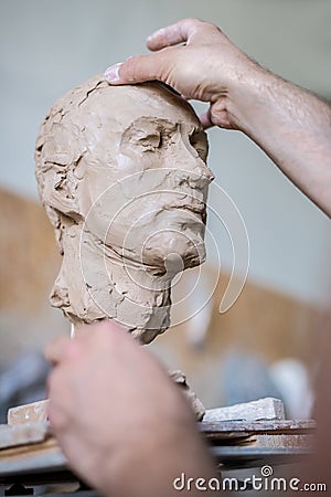 A sculptor sculpts a sculpture of a person`s face. Horizontal frame Stock Photo