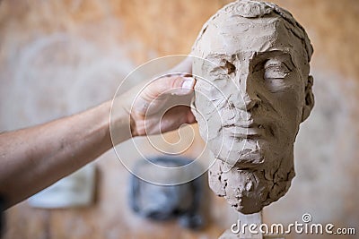 A sculptor sculpts a sculpture of a person`s face. Horizontal frame Stock Photo