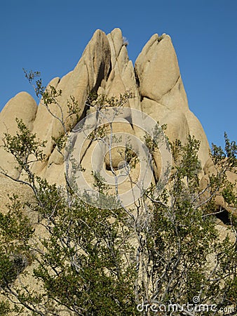 Sculptural granite rock formation with triangular peaks set against a blue Mojave Desert sky Stock Photo